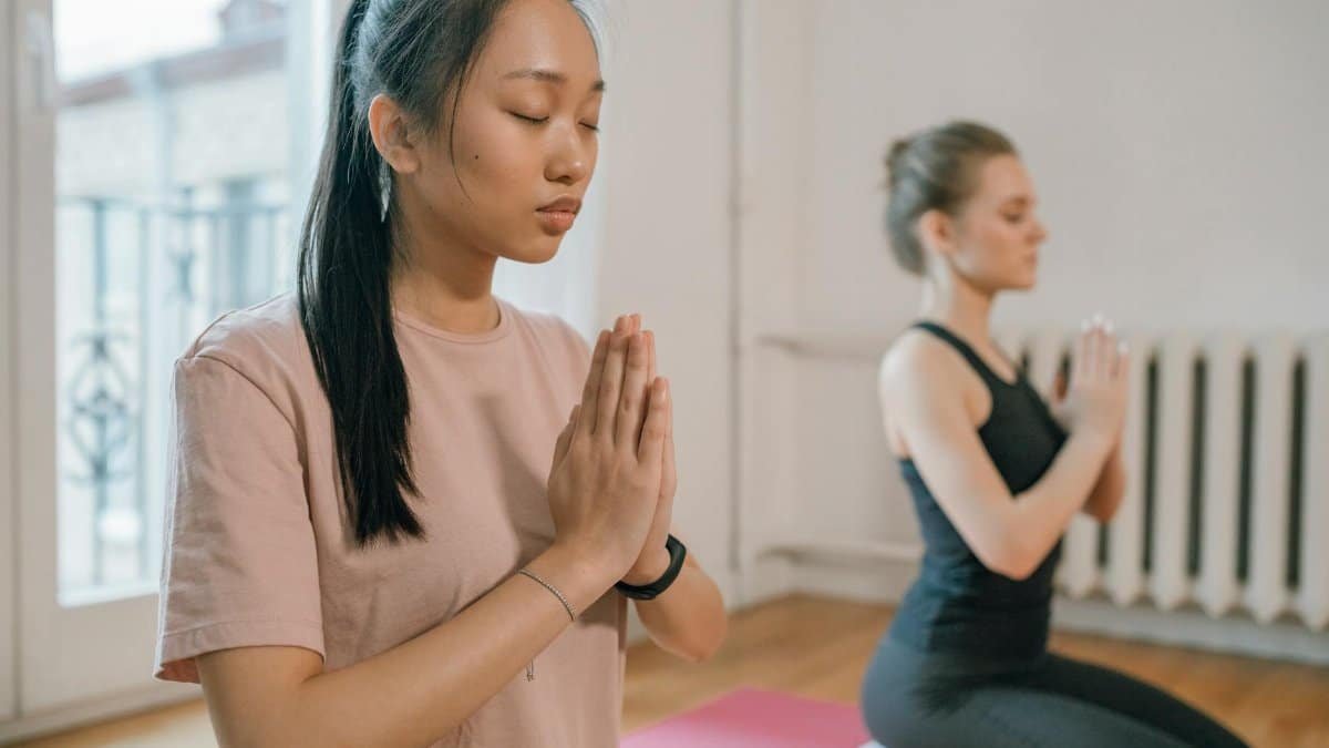 Two women engaging in a serene yoga practice, focusing on meditation for mental wellness.