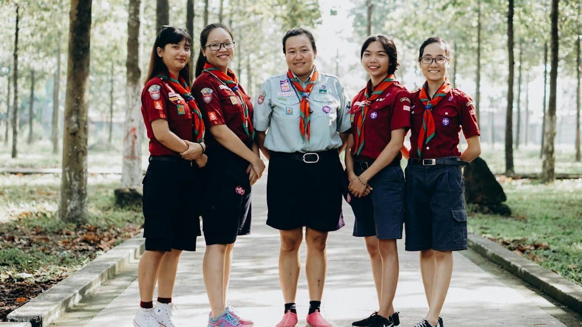 A group of young scout leaders posing in uniform in a forest setting, showcasing teamwork and unity.
