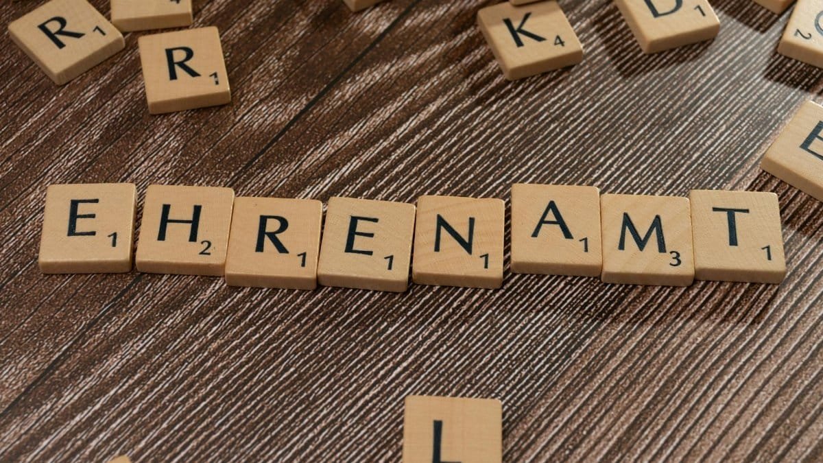 Scrabble tiles spelling 'Ehrenamt' on a wooden background. Perfect for volunteerism themes.