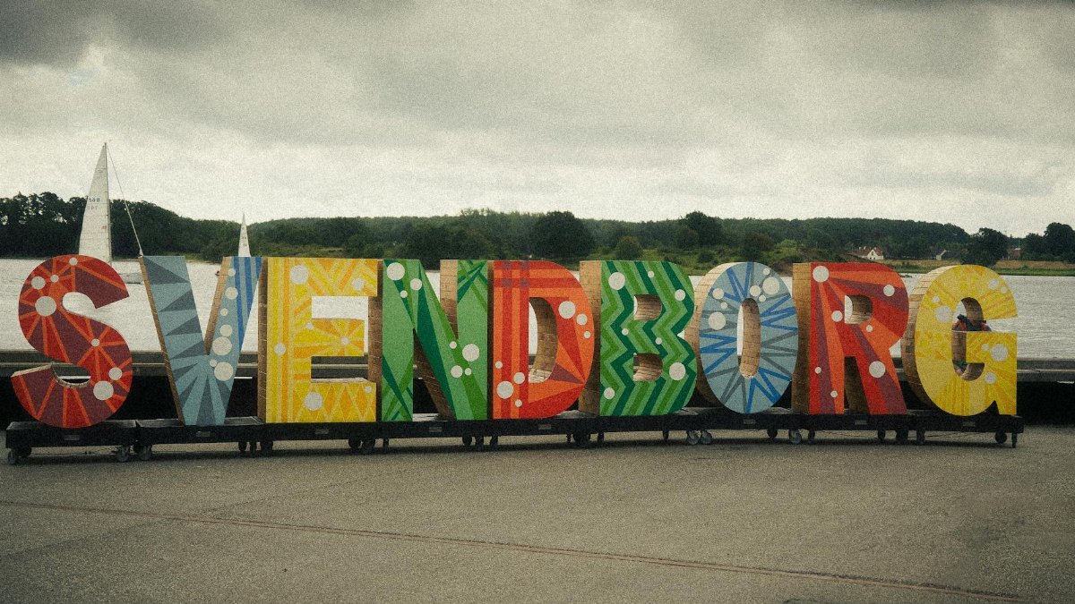 Vibrant Svendborg sign by the waterfront with a cloudy sky, Denmark.