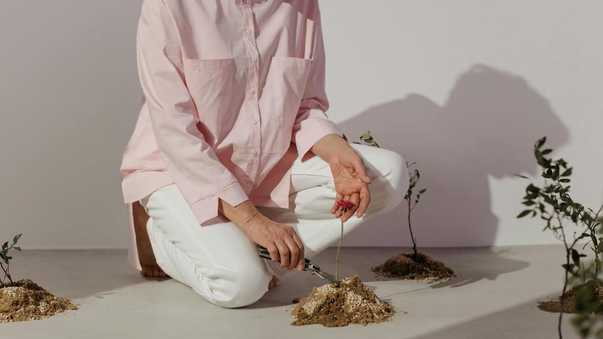 Woman planting and tending to small plants and flowers indoors.