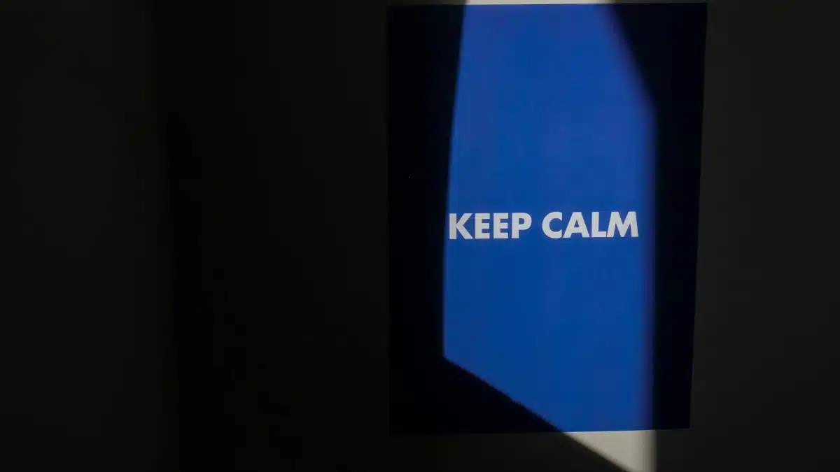 Blue poster with 'Keep Calm' text illuminated by spotlight in dark room.