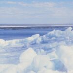 Experience stark beauty at a frozen lake in Minnesota. Capturing peaceful winter landscape with ice floes and blue sky.