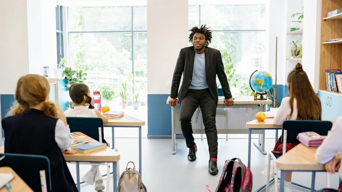 A teacher engages with students in a bright, modern classroom setting, promoting education.