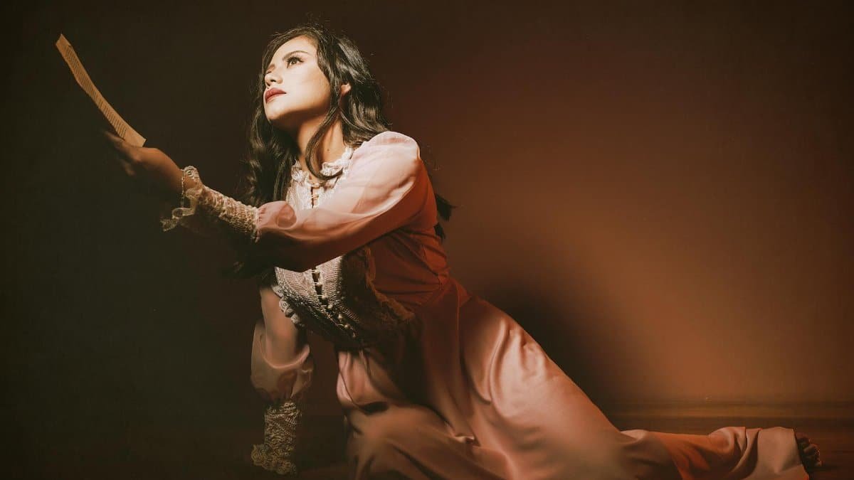 A woman in a vintage dress striking a dramatic pose, capturing the essence of theatrical performance.