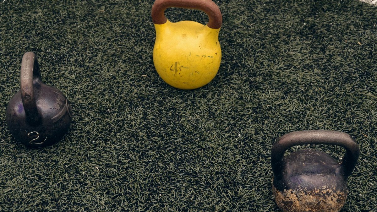 Three kettlebells on an outdoor grassy surface, perfect for fitness enthusiasts.