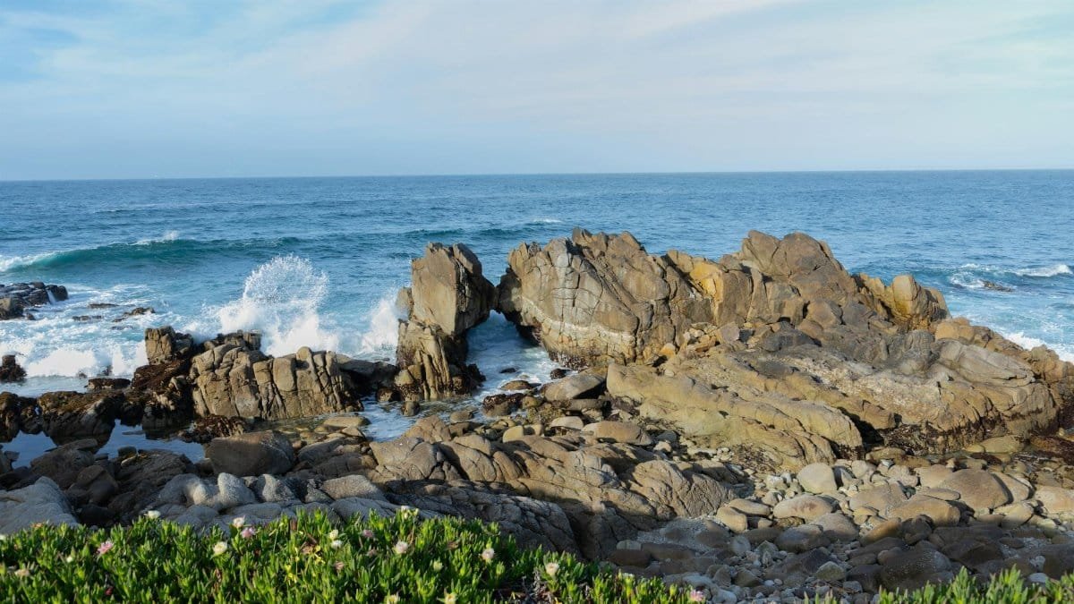 Scenic seascape of rocky shoreline and crashing waves in Monterey, California.