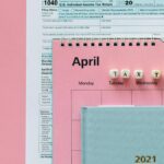 Flat lay image of tax forms, calendar, and 'tax time' reminder on a pink background.