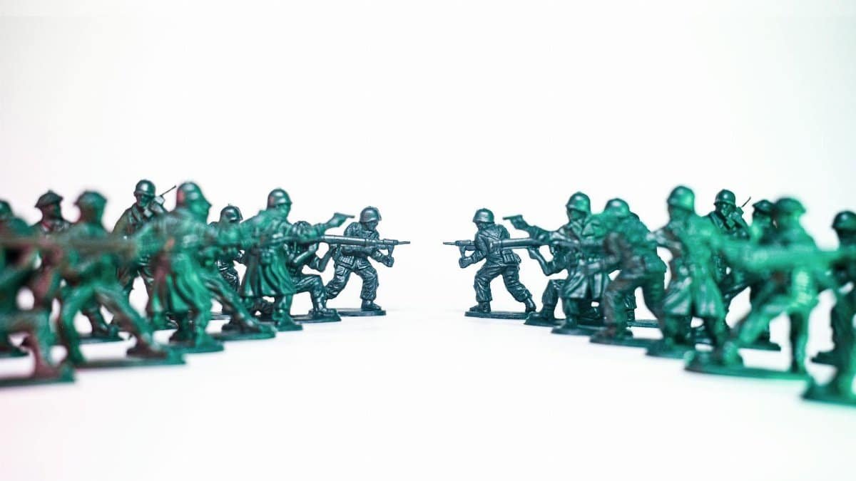 Green toy soldiers facing off on a white background, symbolic of conflict and strategy.