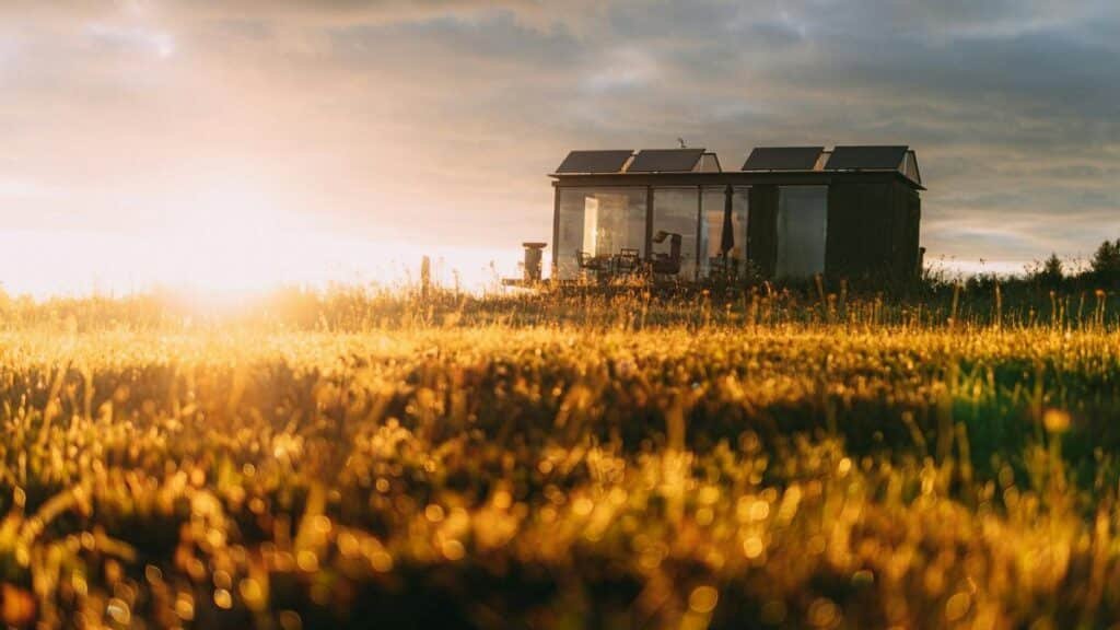 A picturesque tiny house with solar panels in a golden field during sunset, capturing eco-friendly living.