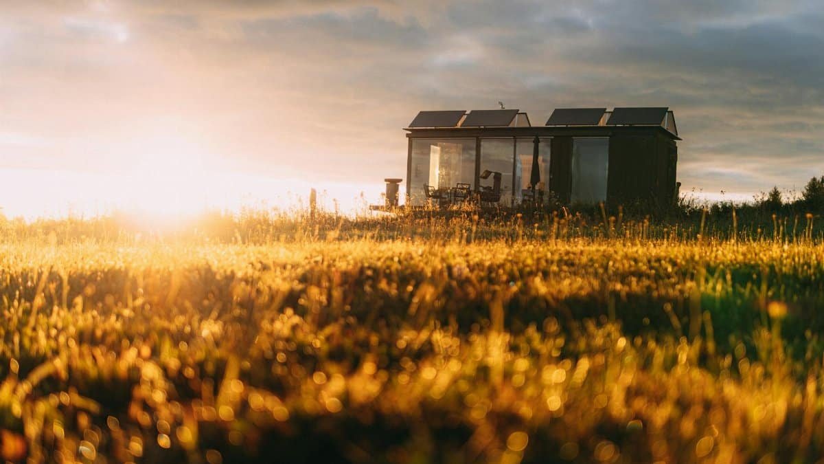 A picturesque tiny house with solar panels in a golden field during sunset, capturing eco-friendly living.