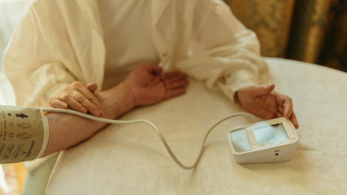 A senior adult checking their blood pressure with a digital monitor at home.