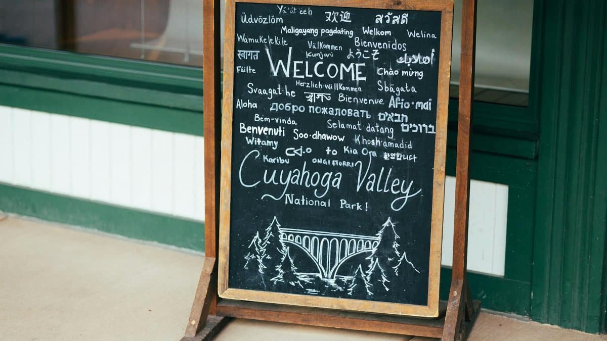 Chalkboard sign welcoming visitors to Cuyahoga Valley National Park in various languages.