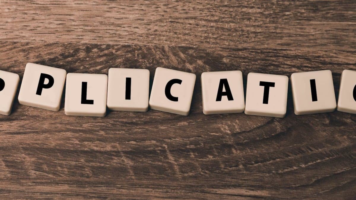 Scrabble letter tiles spelling 'application' on a wooden surface.