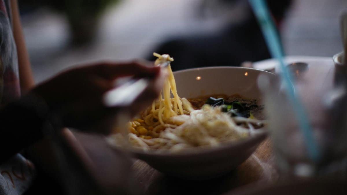 Close-up of a bowl of freshly served Asian noodle soup with chopsticks.