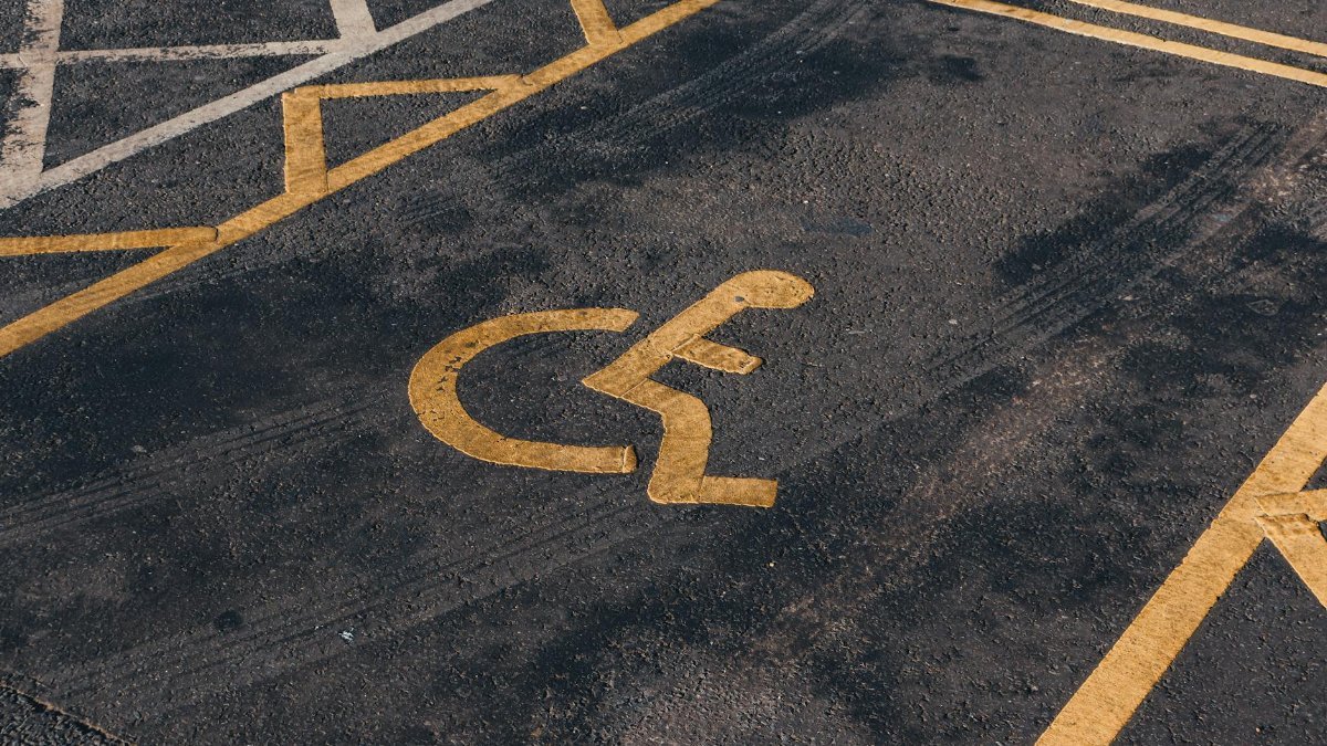 Close-up view of an international accessibility symbol painted on a parking lot surface.