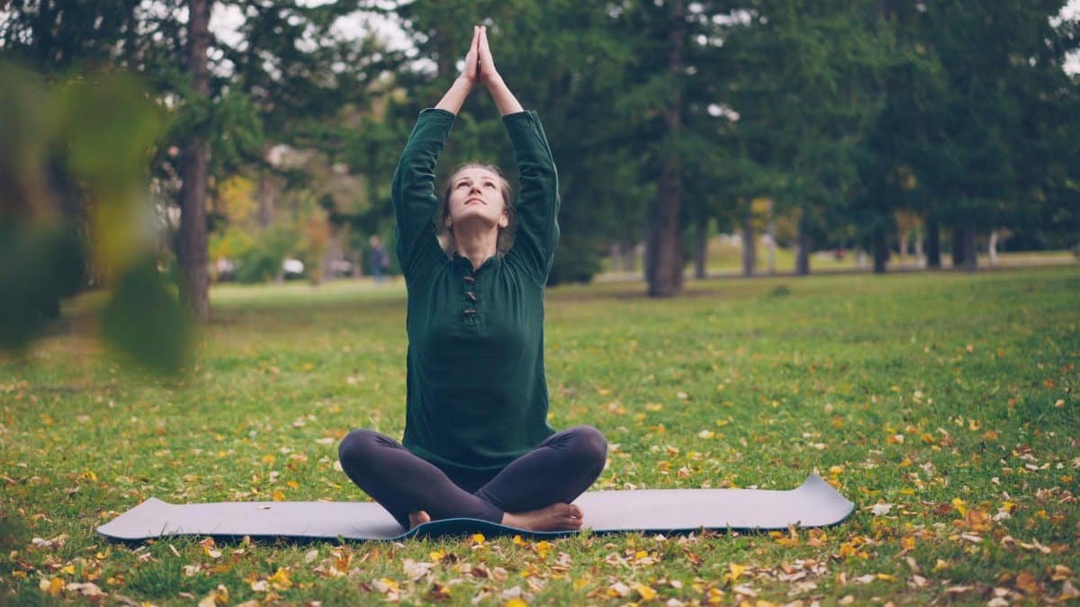 Adult woman practicing yoga in a serene park setting during fall