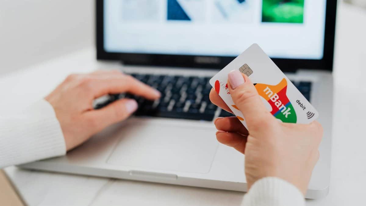 Close-up of hands using a laptop and holding a credit card for an online transaction.