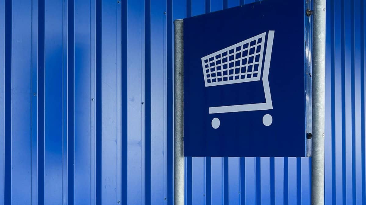 Blue metal wall with a shopping cart sign symbolizing retail or supermarket area.