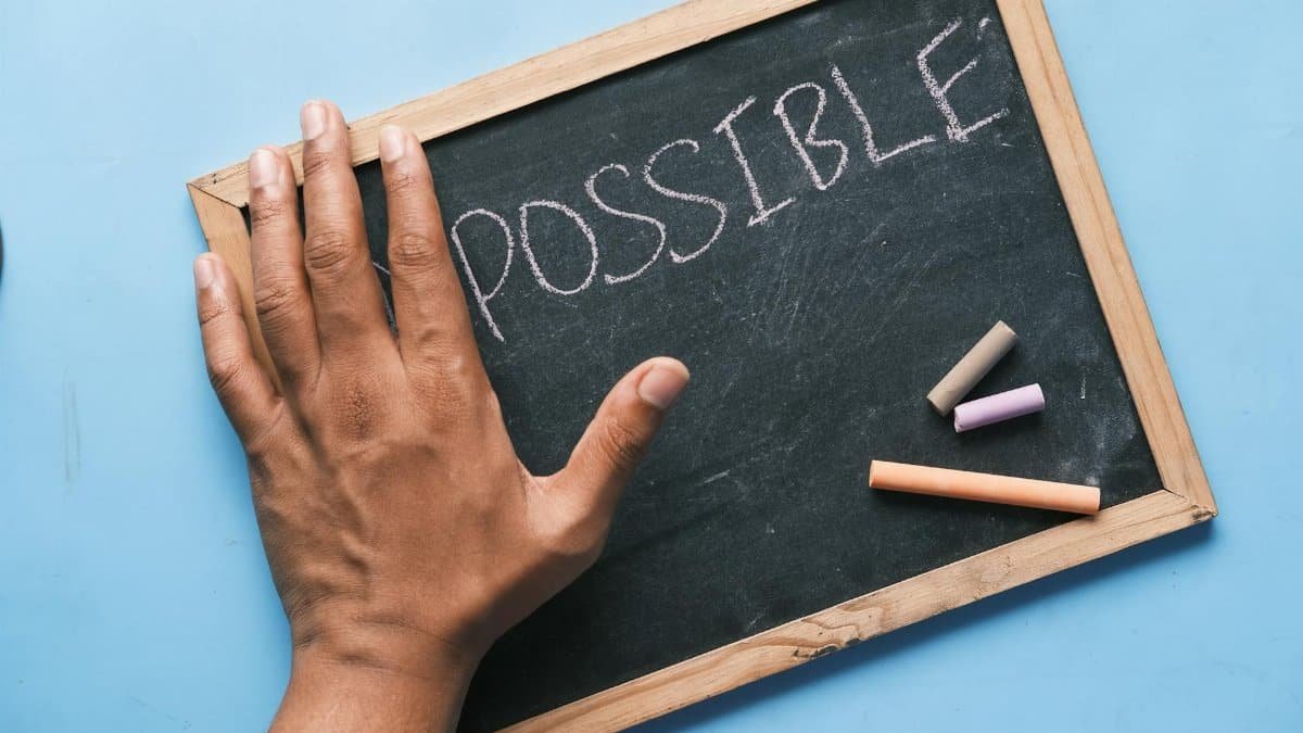 A hand on a chalkboard with 'Possible' written in chalk signifies optimism and potential.
