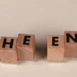 Wooden blocks arranged to spell 'The End' on a simple beige background, symbolizing closure.