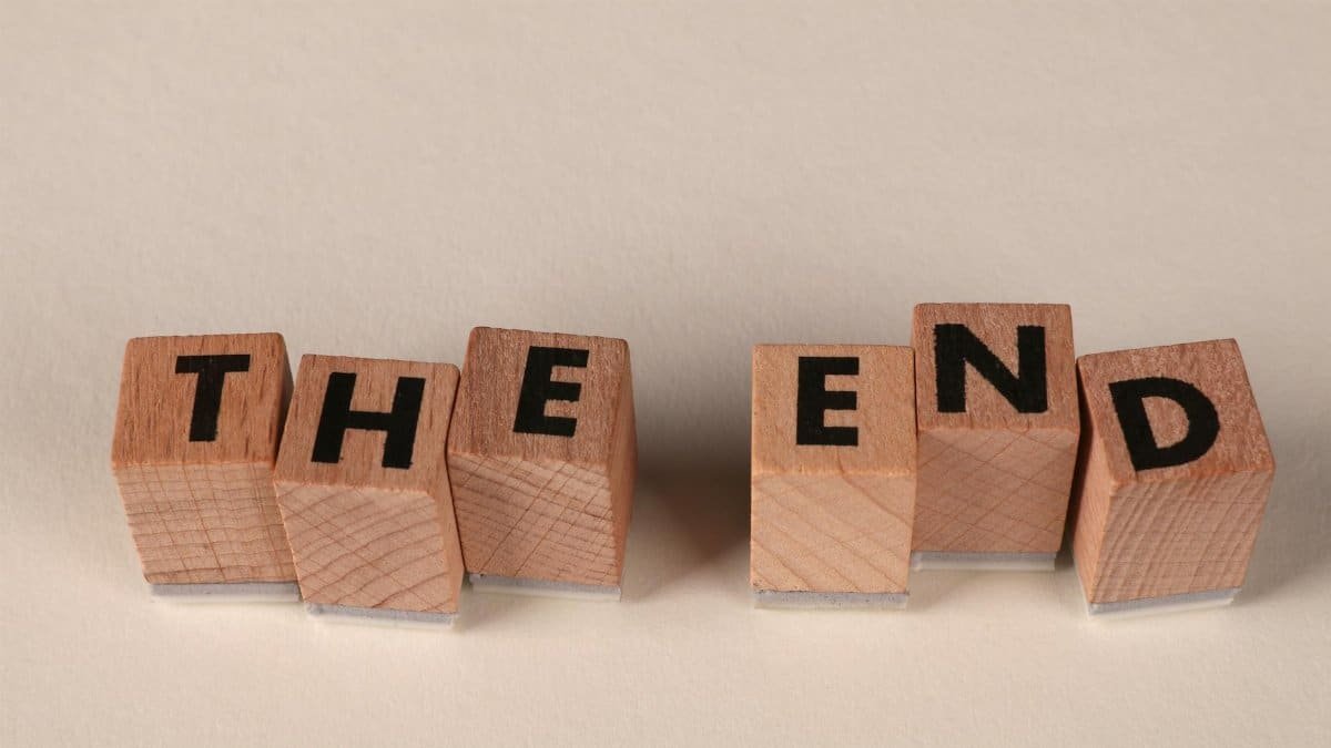 Wooden blocks arranged to spell 'The End' on a simple beige background, symbolizing closure.