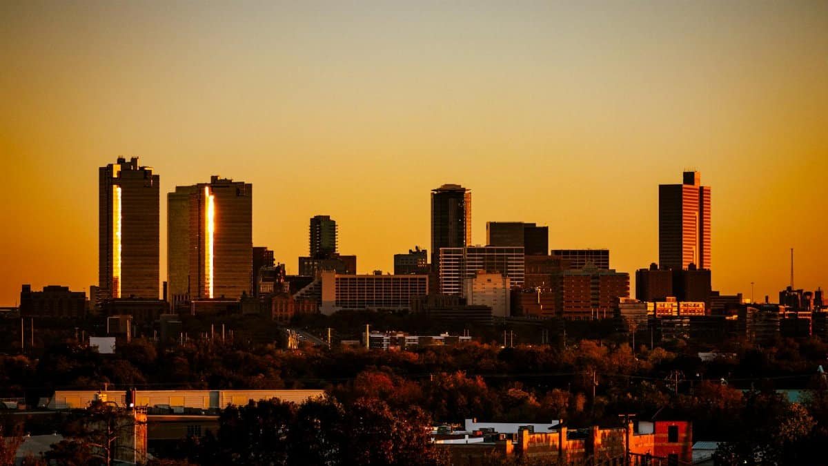 Dramatic sunset view of Fort Worth, Texas skyline. Warm tones highlight the city's architecture.