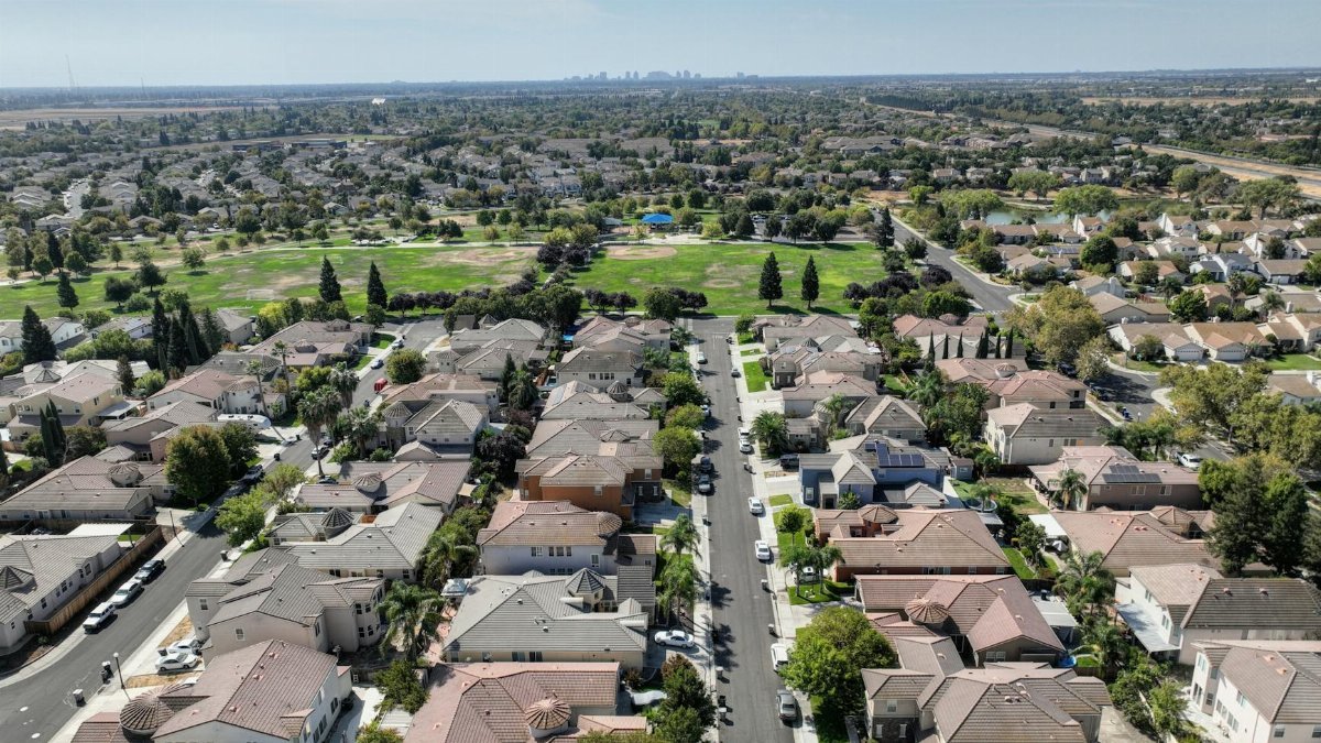 Scenic aerial view of Sacramento suburb with rows of houses and lush greenery on a sunny day.