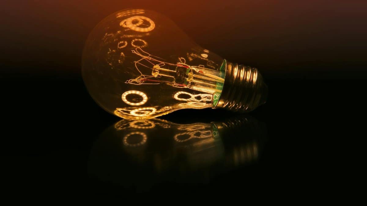 A glowing light bulb on a dark reflective surface creating a warm ambient atmosphere.