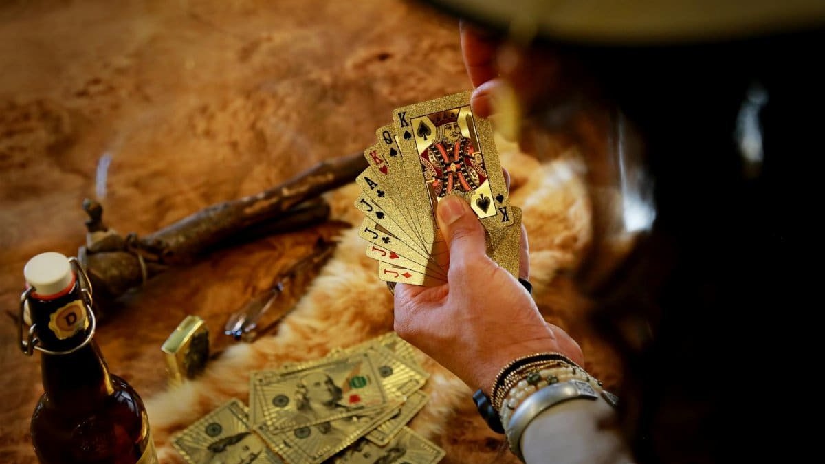 Hand holding playing cards in a Las Vegas casino scene, showcasing gambling elements.