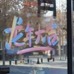 Vibrant New Year 2024 storefront window display with festive artistic lettering.