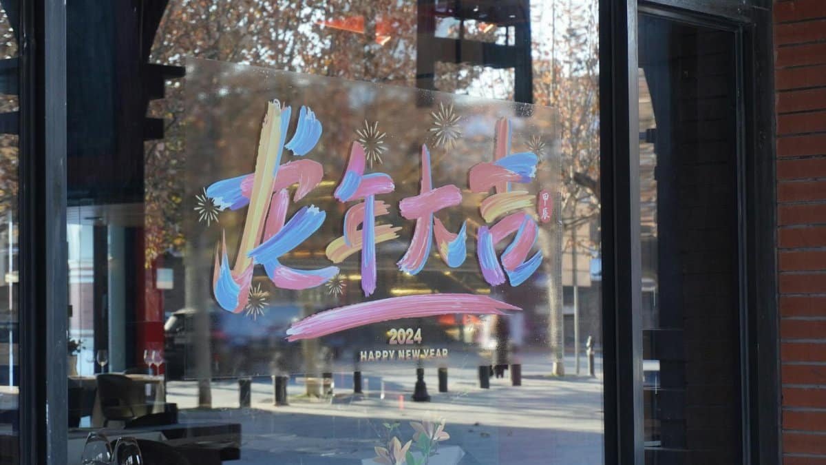 Vibrant New Year 2024 storefront window display with festive artistic lettering.