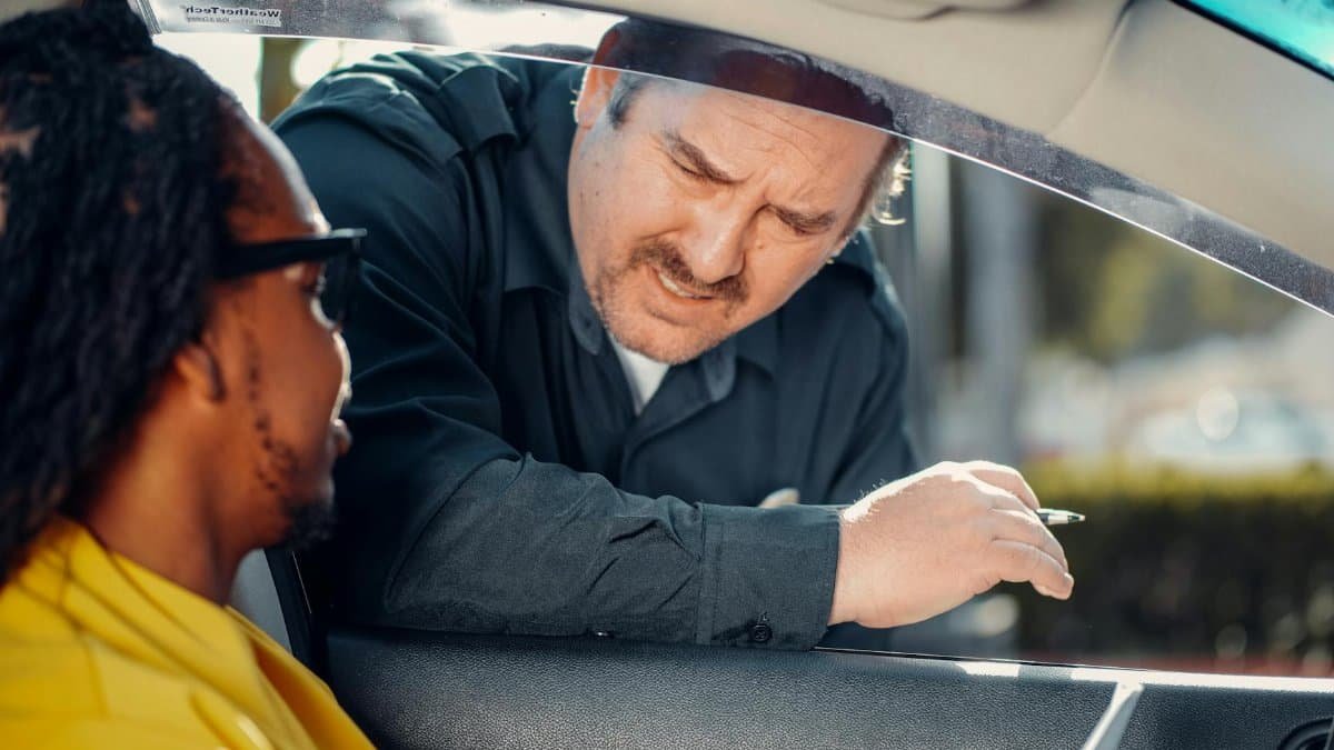 A police officer interacts with a driver through a car window, emphasizing law enforcement and public safety.