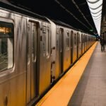 Image of a New York subway train at an underground station platform with an American flag.