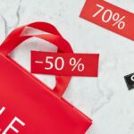 Red sale bag with 50% and 70% discount tags on marble background, perfect for retail promotions.