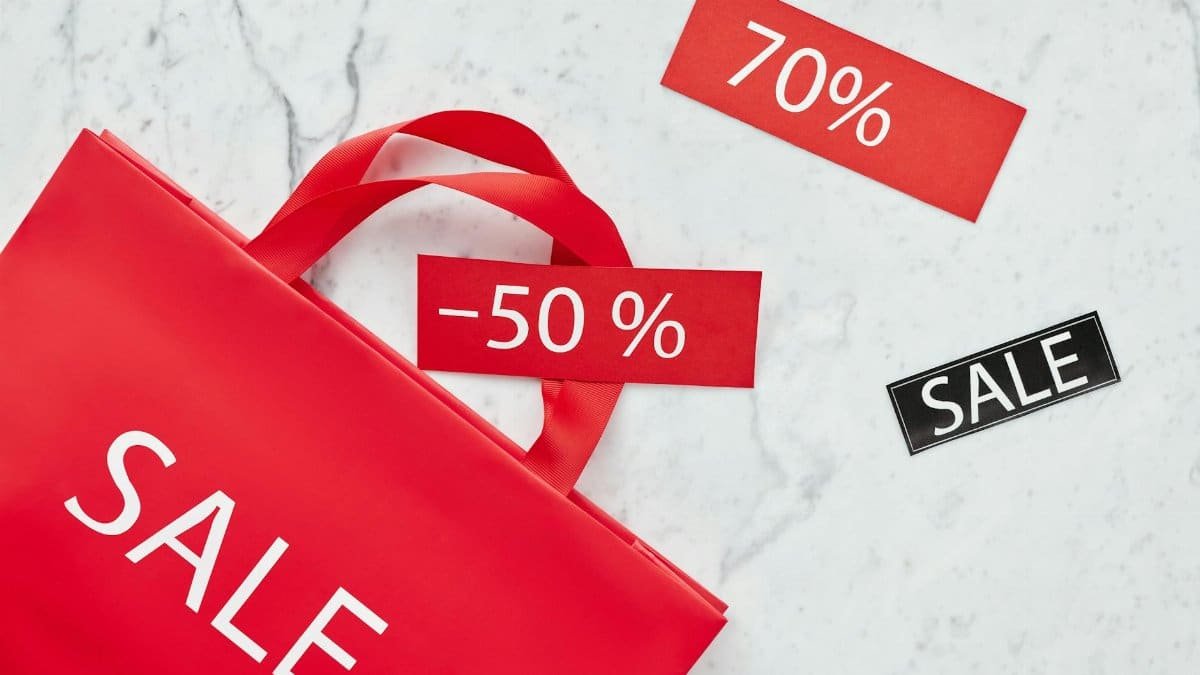 Red sale bag with 50% and 70% discount tags on marble background, perfect for retail promotions.