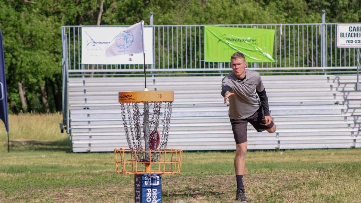 A man throws a disc towards the basket during a disc golf tournament in Clearwater, MN.