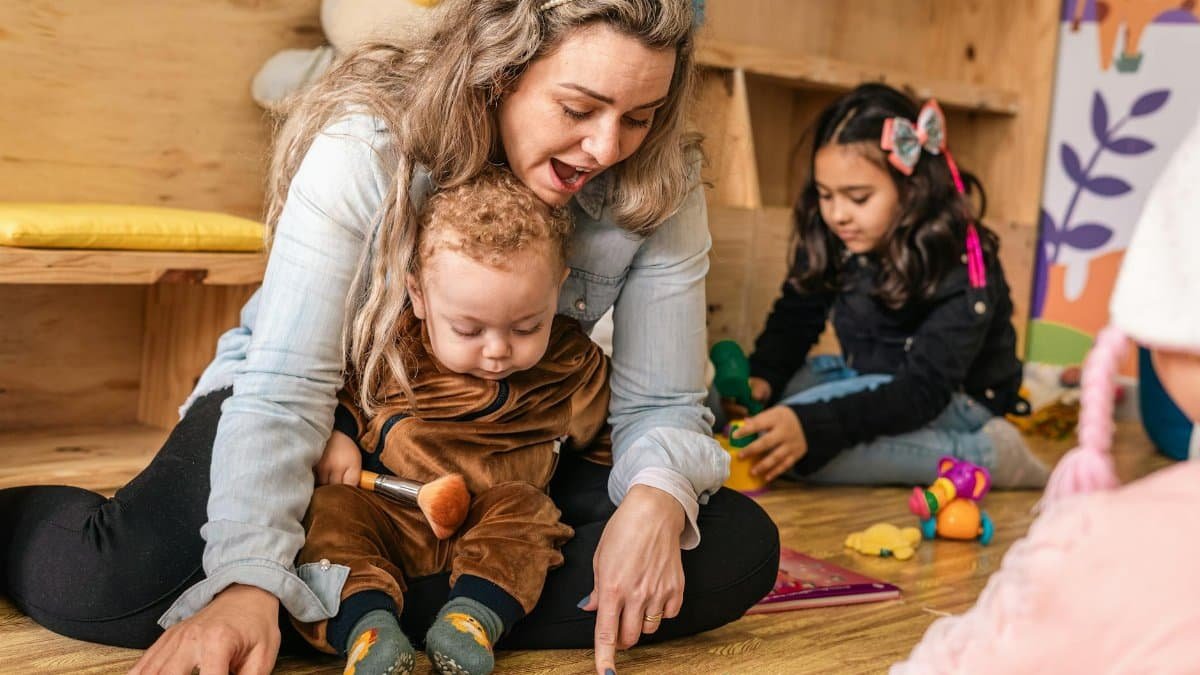 A mother and children enjoying interactive playtime on the floor in a cozy indoor setting.