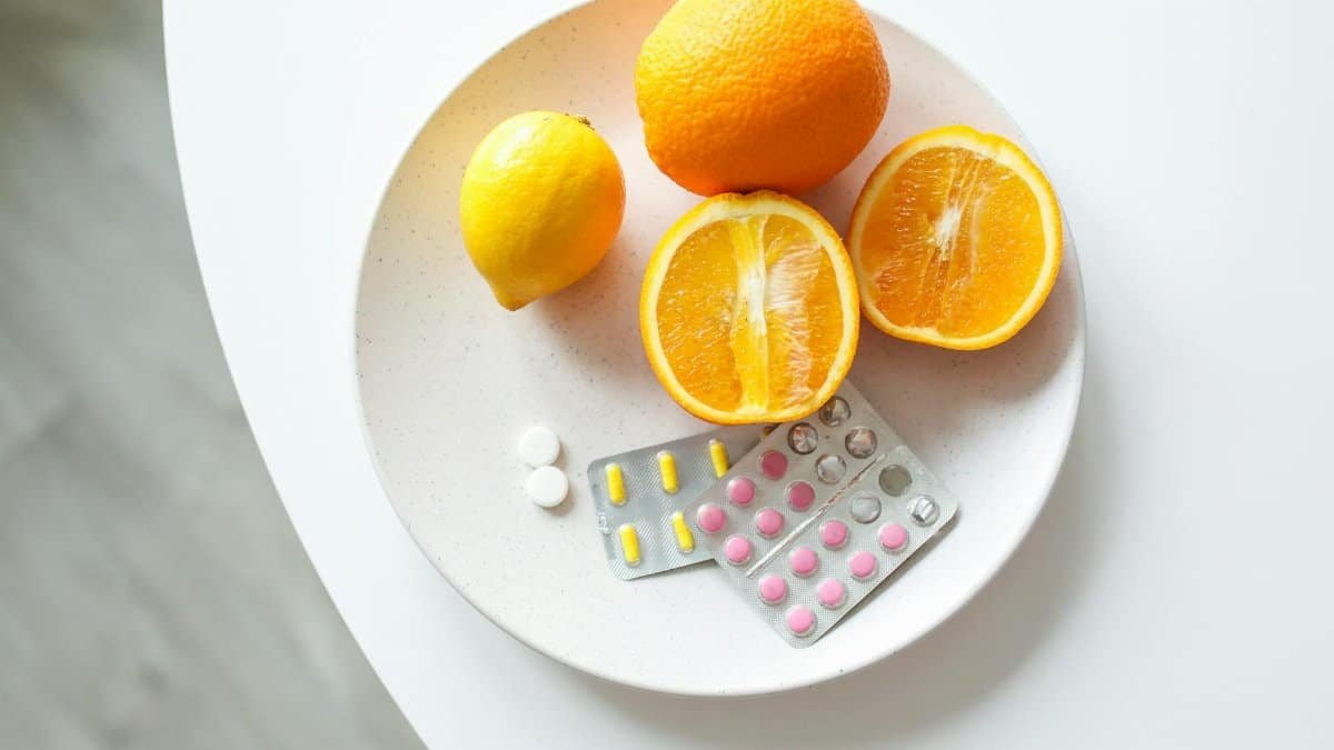 A plate of fresh citrus fruits and blister packs of pills, highlighting nutrition and healthcare.