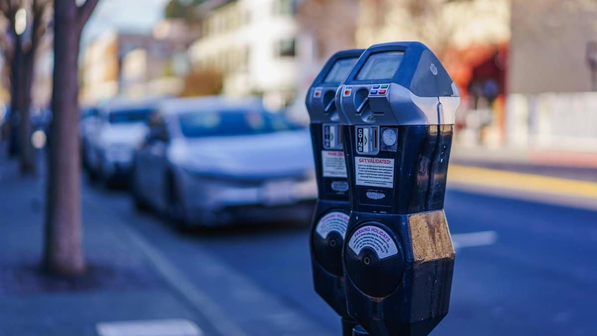 Close-up of parking meters in a bustling city street during the day, showcasing urban infrastructure.