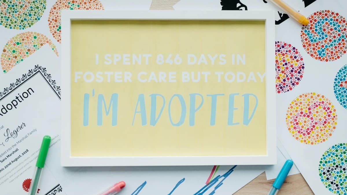 Framed adoption announcement with art and pens, celebrating new beginnings.