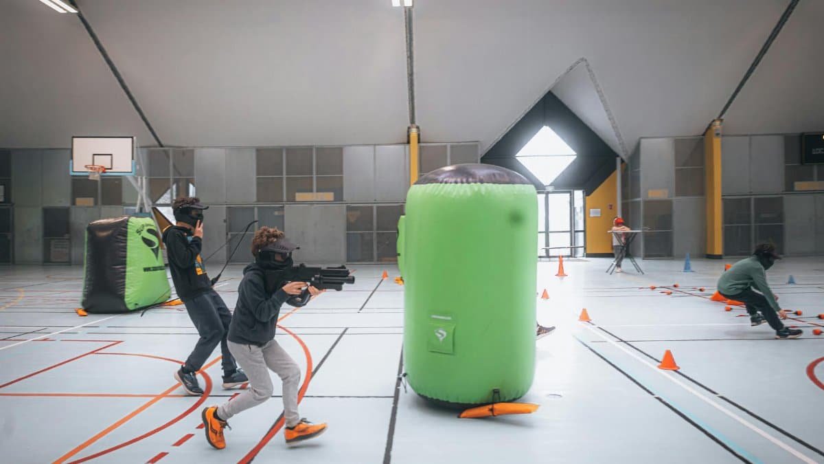 Energetic teenagers playing an indoor laser tag game with vibrant inflatables and obstacles.
