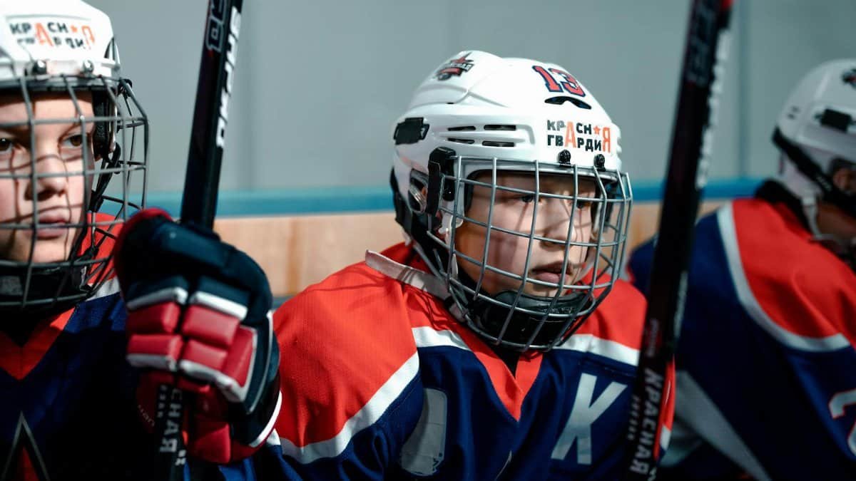 Close-up of young ice hockey players with sticks and helmets, ready for a game on the rink.