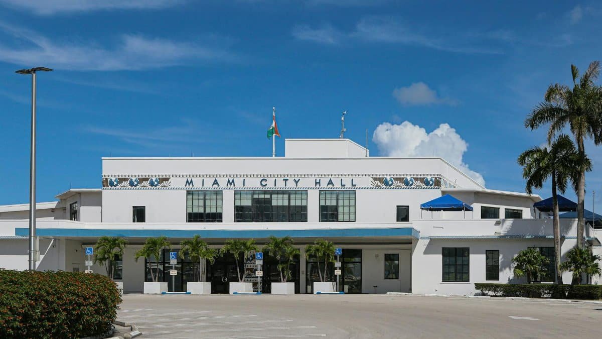 Front view of Miami City Hall with palm trees under a clear blue sky.