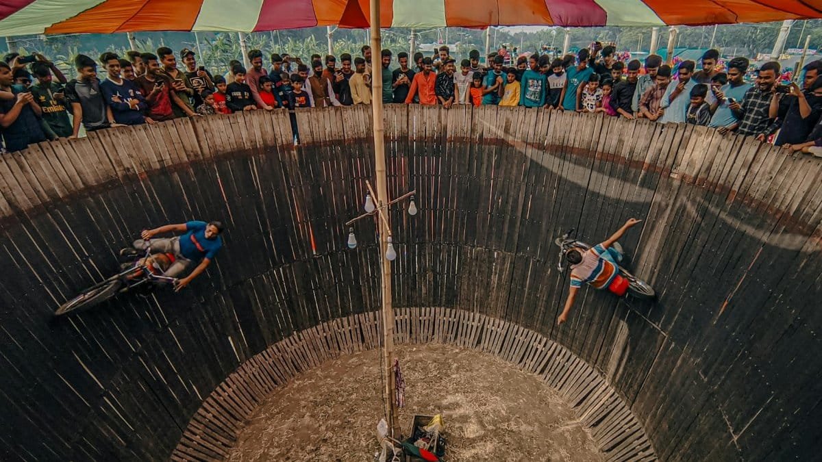 Motorcycle stunt riders defy gravity in Wall of Death at a vibrant carnival in Cumilla, Bangladesh.