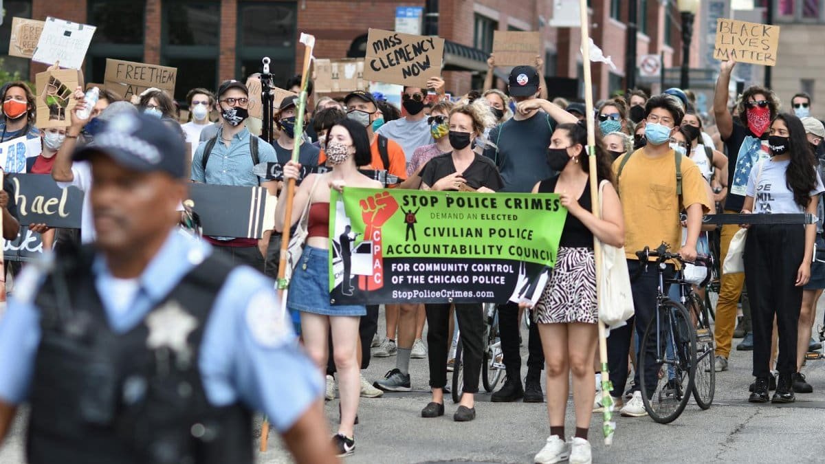 Protesters march in Chicago demanding police accountability. Diverse crowd carries signs for justice.