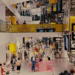 Vibrant mall filled with shoppers, contemporary decor, and stylish fashion outlets.