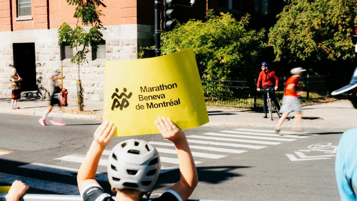 Child holds sign supporting runners at Montreal marathon, capturing athletic energy.