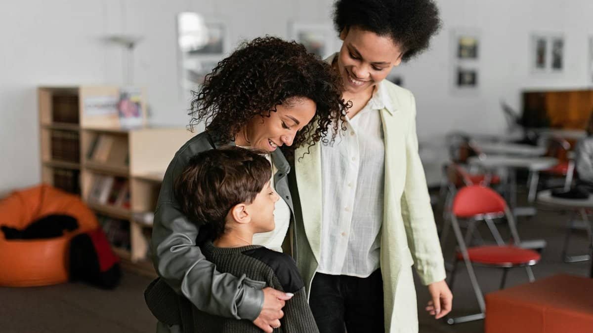 Heartwarming family scene with two mothers and their son in a classroom setting.