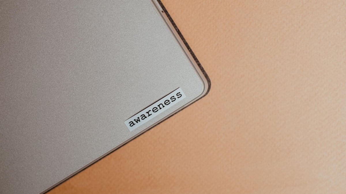 Close-up of a beige laptop with an awareness sticker, promoting mindfulness and digital organization.